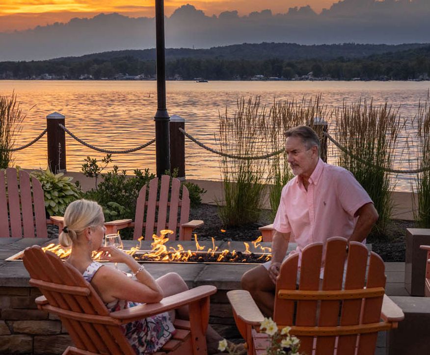 A couple enjoys time by the fire pits and watches a beautiful sunset at the Chautauqua Harbor Hotel