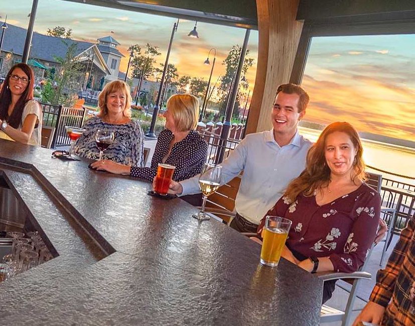 A group of people enjoying cocktails at the Carousel Bar in front of a beautiful sunset