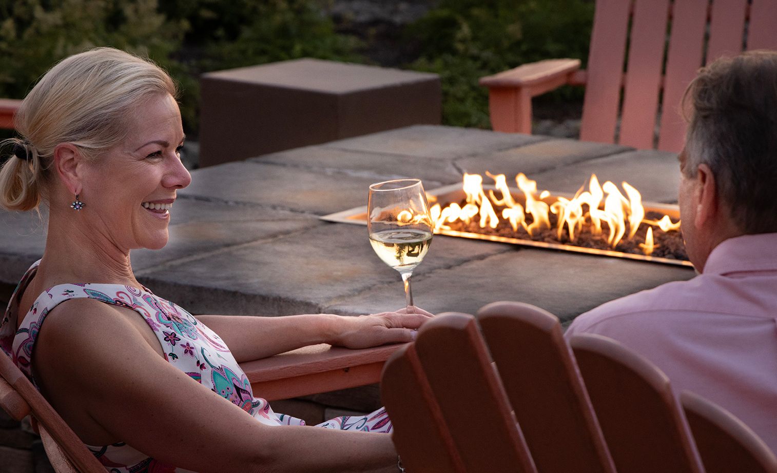 A couple enjoying a glass of wine by a fire pit at the Chautauqua Harbor Hotel