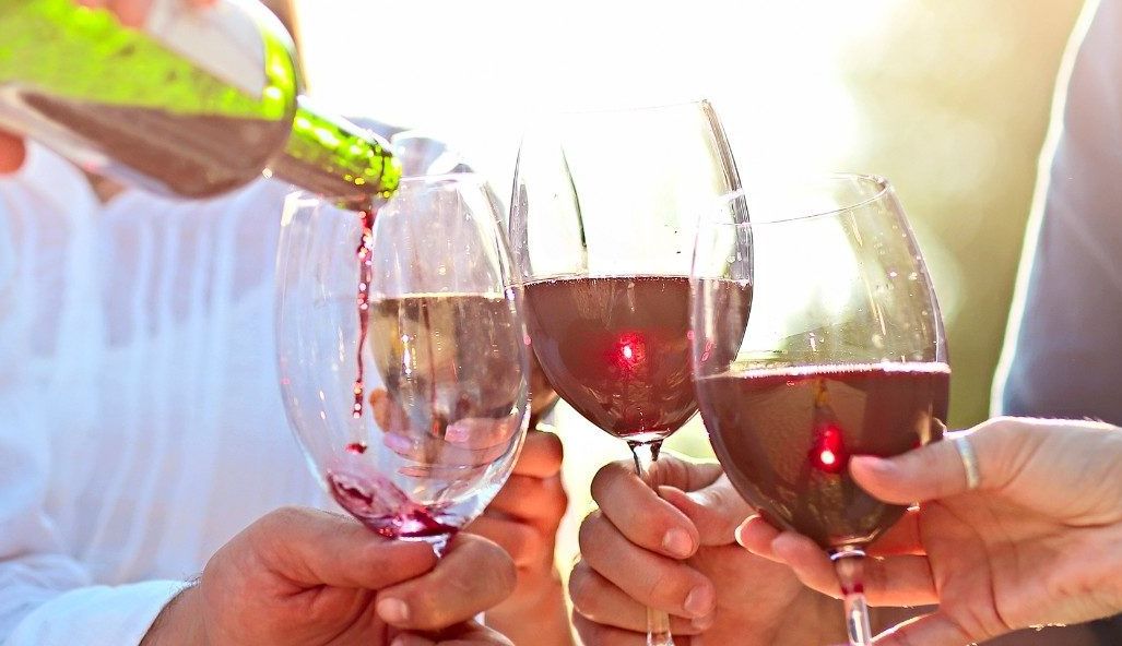 Several couples pouring a bottle of wine in the sunshine